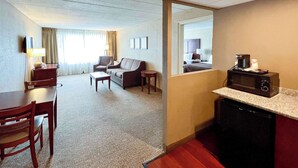 Habitación de hotel con comedor, sofá, cafetera y microondas.