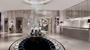 A modern lobby with a central reception desk, a chandelier, and a staircase leading to upper floors. - The Park Tower Knightsbridge, A Luxury Collection Hotel (London)