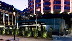 A tall, modern hotel with a curved facade and illuminated windows. - The Park Tower Knightsbridge, A Luxury Collection Hotel (London)