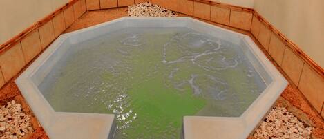 A hot tub with a wooden ceiling and tiled walls.
