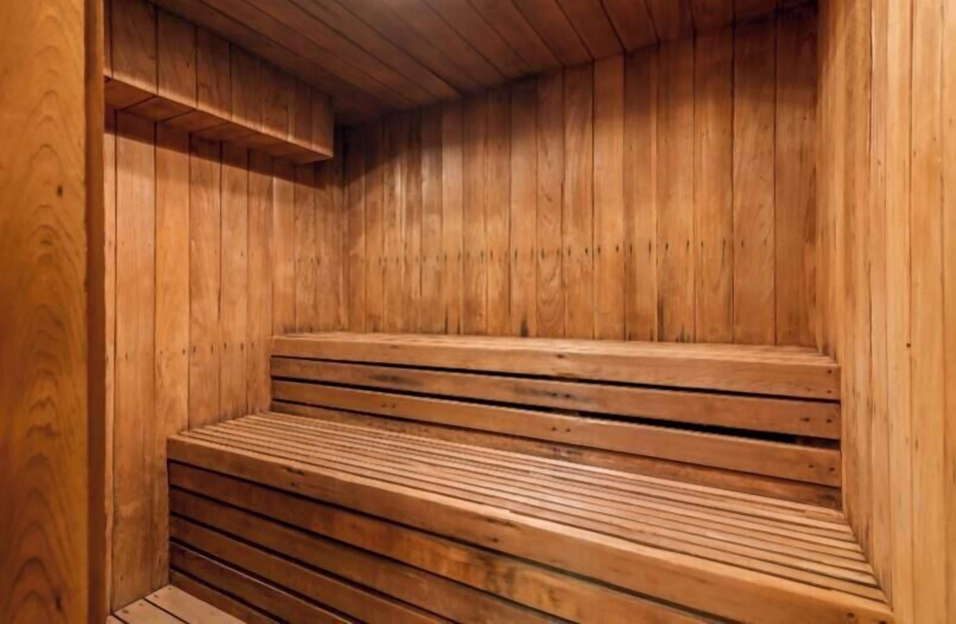 Sauna de fusta amb bancs i una prestatgeria.