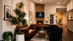 A hotel lobby with a leather sofa, a wooden reception desk, a flat-screen TV, and a fireplace. - Clarion Hotel & Conference Center Lewiston (Lewiston)