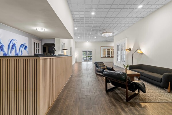 A reception area with a wooden counter, a sofa, and a lounge chair.