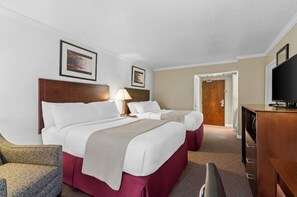A hotel room with two beds, a TV, a desk, and a chair.