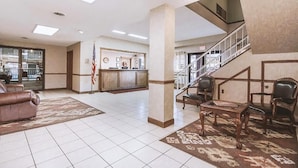 Eine großzügige Lobby mit Treppe, einer Rezeption und Sitzbereichen.