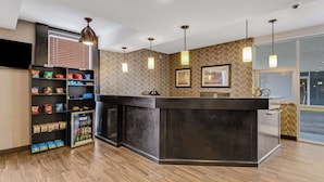 A reception area with a dark counter, shelves with snacks, a refrigerator, and pendant lighting. - Best Western Inn of Del Rio (Del Rio)