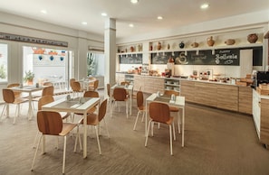 A restaurant interior with wooden tables and chairs, a chalkboard menu, and a variety of pottery displayed on shelves. - Hotel Sercotel Puerto de Santa María (El Puerto de Santa Maria)