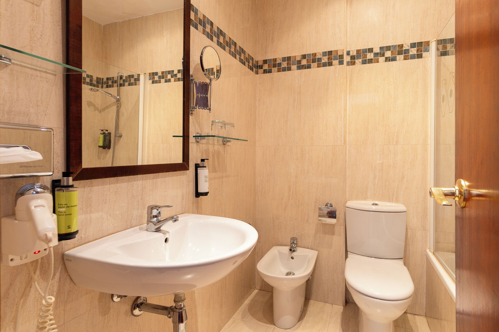 Un baño con lavabo, bidé, inodoro y cabina de ducha de vidrio.