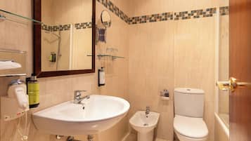 Un baño con lavabo, bidé, inodoro y cabina de ducha de vidrio.