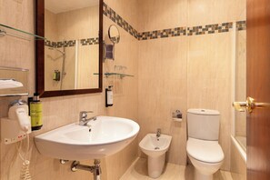 Un baño con lavabo, bidé, inodoro y cabina de ducha de vidrio.