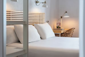 Una cama bien hecha con sábanas blancas, cabecero de madera y dos lámparas de noche.