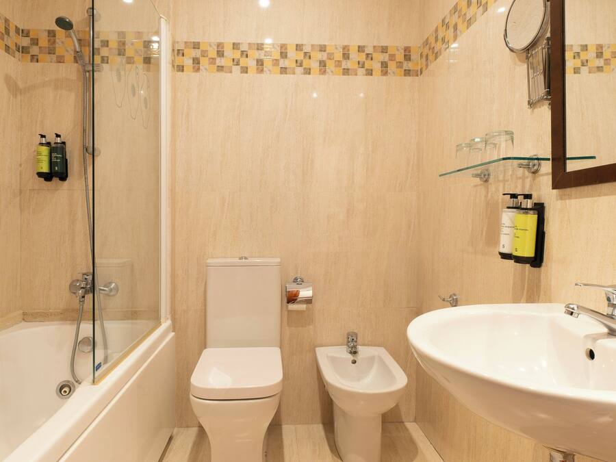 Une salle de bain équipée d’une baignoire, de toilettes, d’un bidet et d’un lavabo.