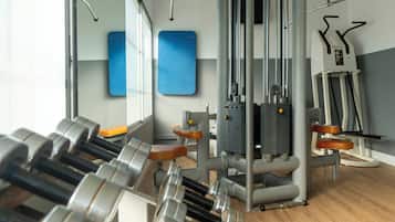 Ein Fitnessraum mit Gewichte, Trainingsgeräten und einem Spiegel.