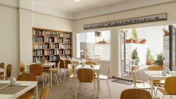 Une bibliothèque avec des étagères, des tables, des chaises et une vue sur l’extérieur.