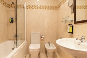 Un baño con bañera, inodoro, bidé y lavamanos.
