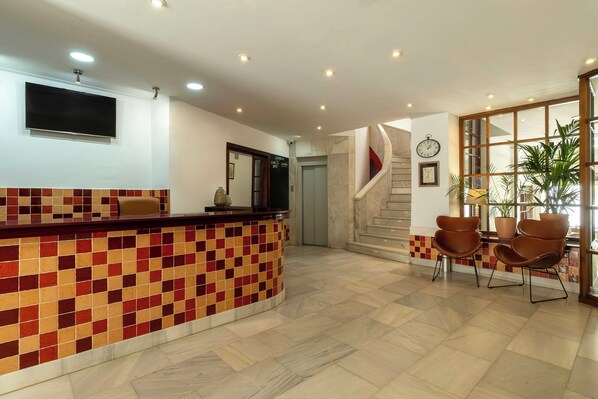 A reception area with a tiled counter, a clock, and a staircase.