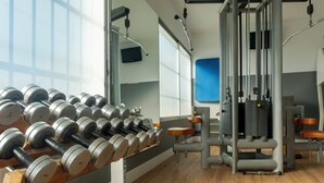 Un gimnasio con equipo de halterofilia, máquinas de ejercicio y un espejo.