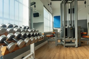 A gym with weightlifting equipment, exercise machines, and a mirror. - Hotel Sercotel Puerto de Santa María (El Puerto de Santa Maria)