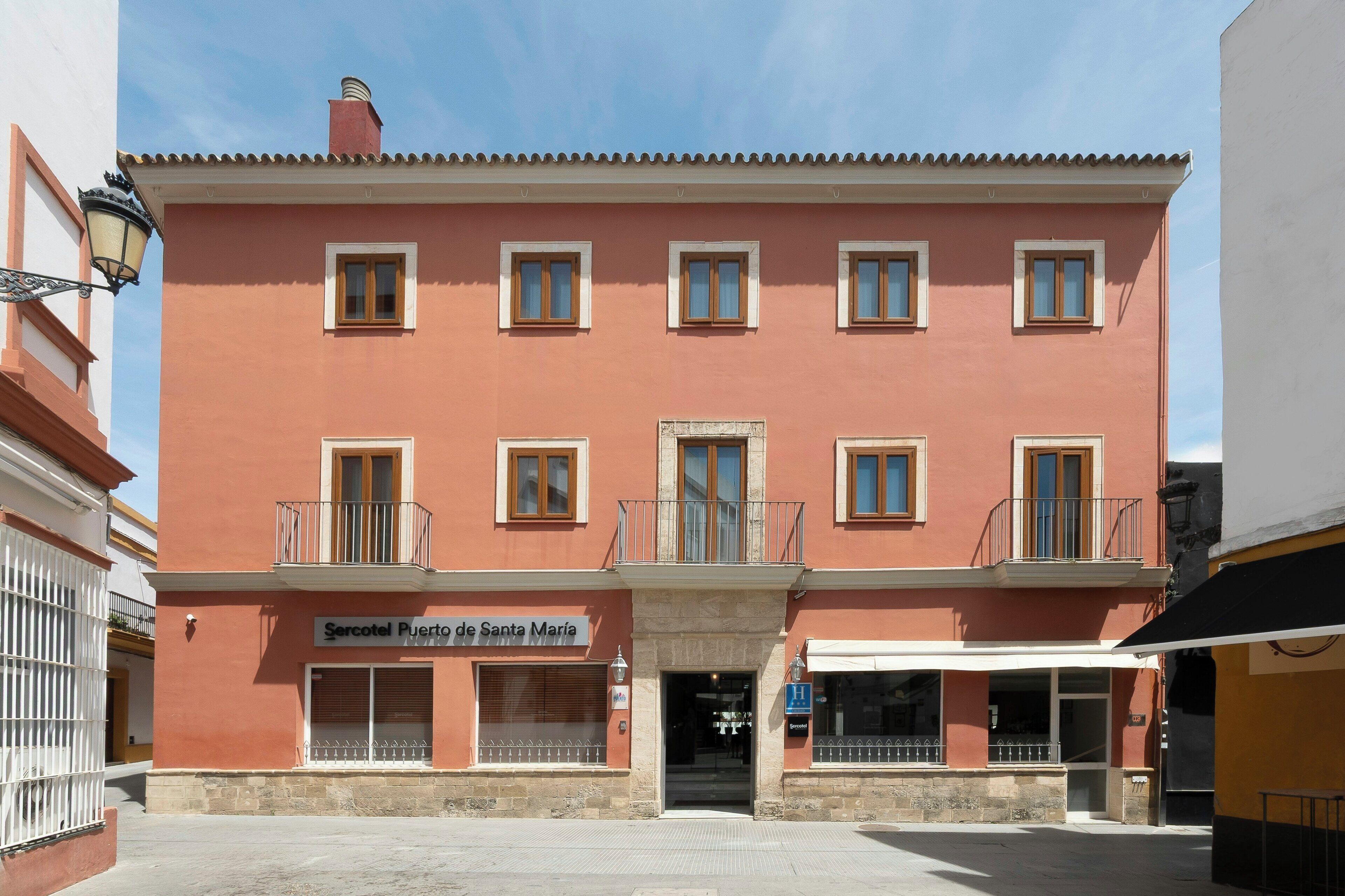 Ein Gebäude mit einem Schild, auf dem 'Sercotel Puerta de Santa María' steht, und einem gut sichtbaren Eingang.