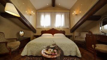 Une chambre à coucher avec un grand lit, deux chaises, une petite table avec un plateau et un lustre.