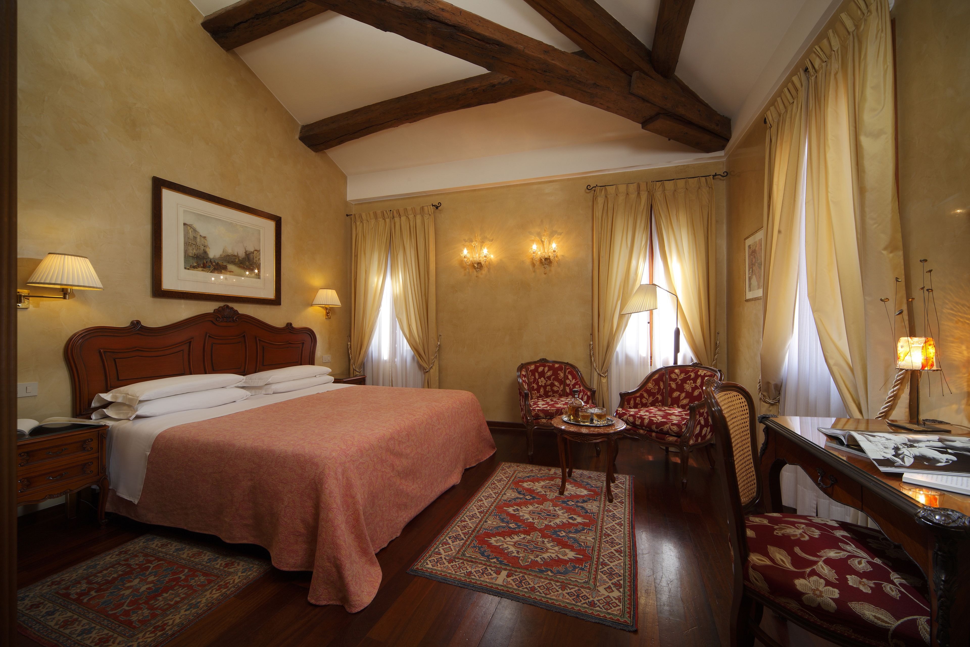 A bedroom with a large bed, two chairs, a small table, and a nightstand.