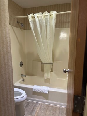 A bathroom with a bathtub, toilet, and shower curtain.