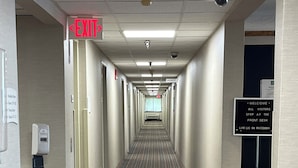 A long, narrow hallway with a tiled floor, a ceiling with recessed lighting, and a sign on the right wall that reads "WELCOME ALL VISITORS STOP AT THE FRONT DESK LIKE US ON FACEBOOK." - Quality Inn Wilkes-Barre near Arena (Wilkes-Barre)