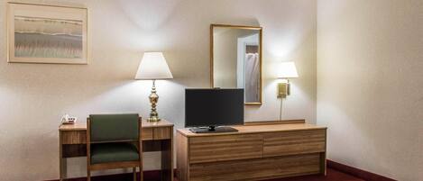 Una habitación de hotel con escritorio, silla, televisor y cama.