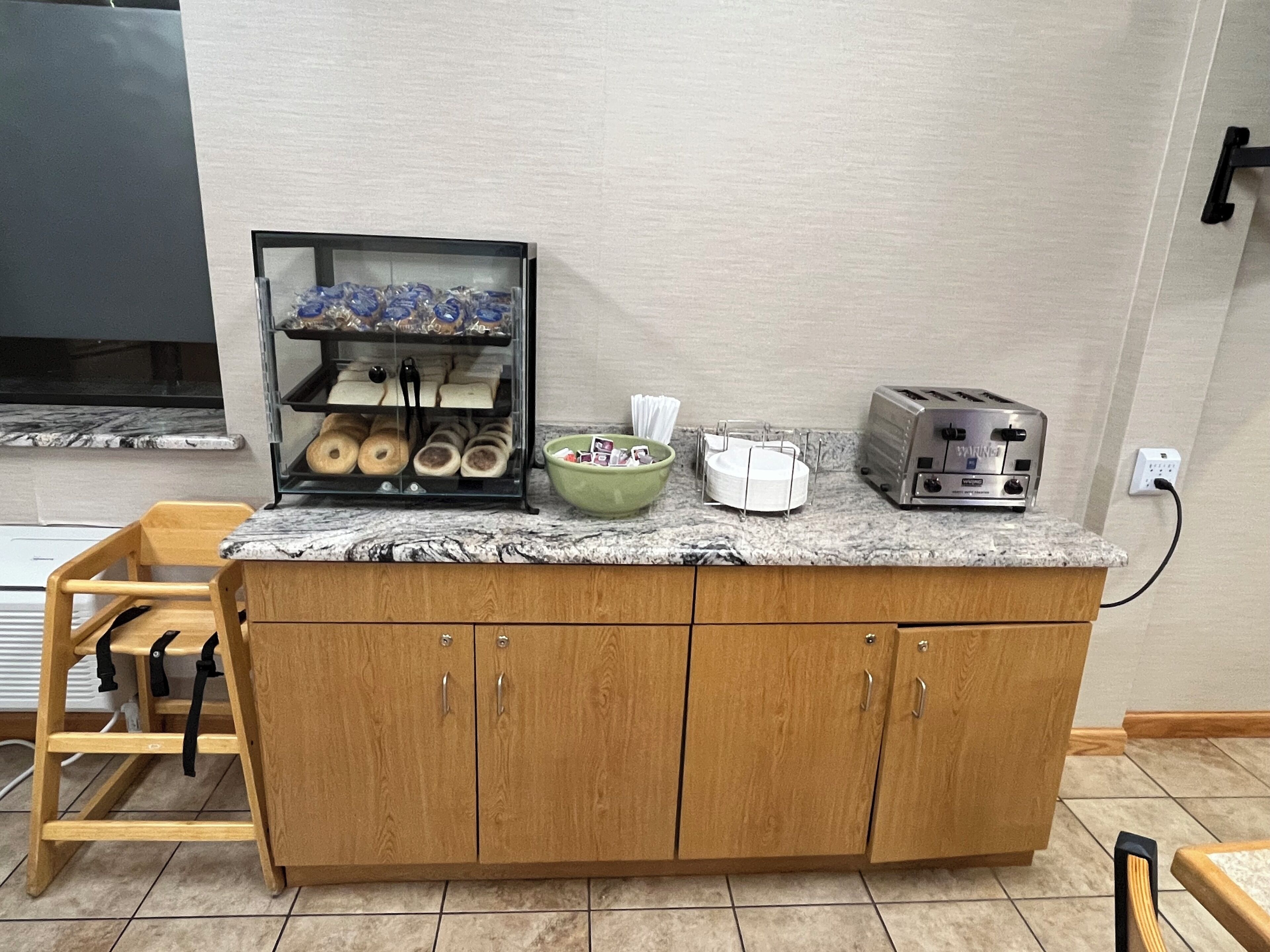 Una encimera de cocina con una exhibición de pan, un bol, un tostador y un armario de madera.