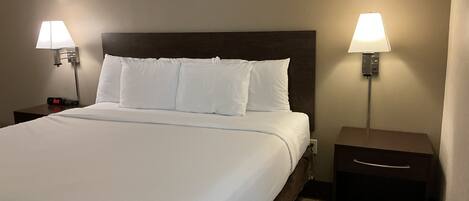 A hotel room with a large bed, two bedside tables, and two wall-mounted lamps.