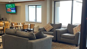 A modern lounge area with grey sofas, patterned throw pillows, and a flat-screen TV displaying a streaming service. - Quality Inn Wilkes-Barre near Arena (Wilkes-Barre)