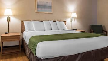 Una habitación de hotel con una cama bien hecha, dos mesitas de noche con lámparas, un edredón verde y un cuadro en la pared.