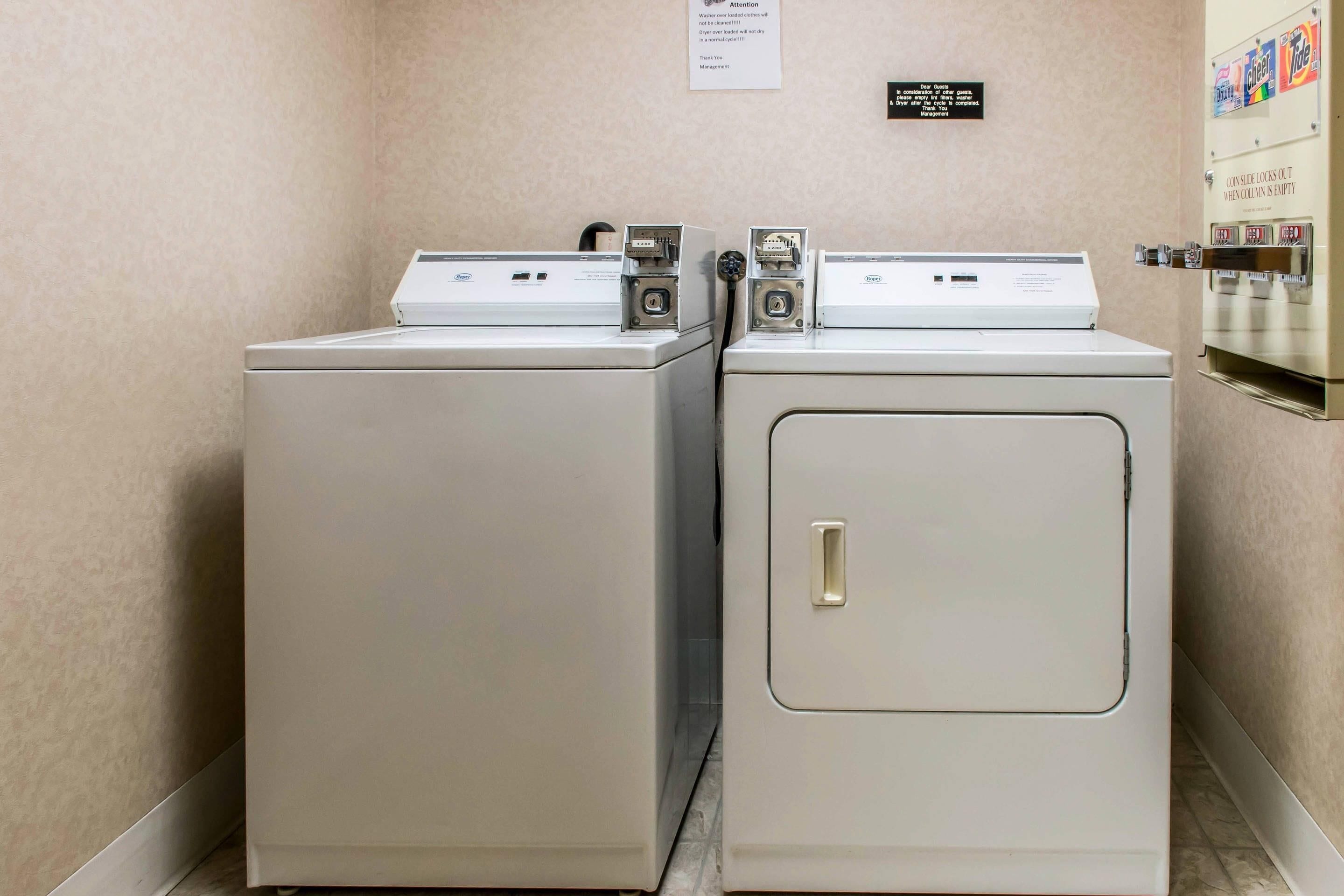 Two front-loading washing machines in a laundry room with a sign above them.