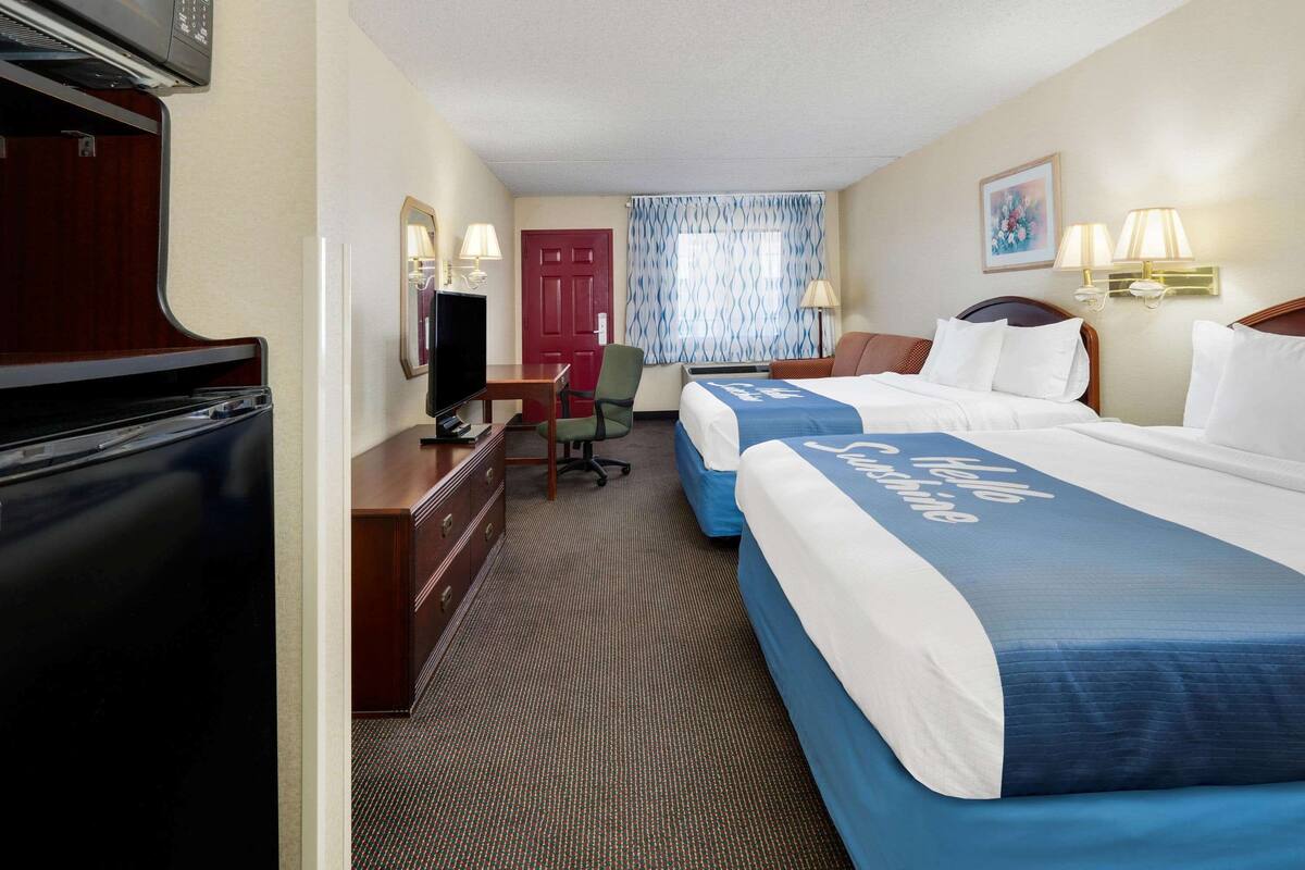 Een hotelkamer met twee bedden, een bureau, een televisie en een magnetron.