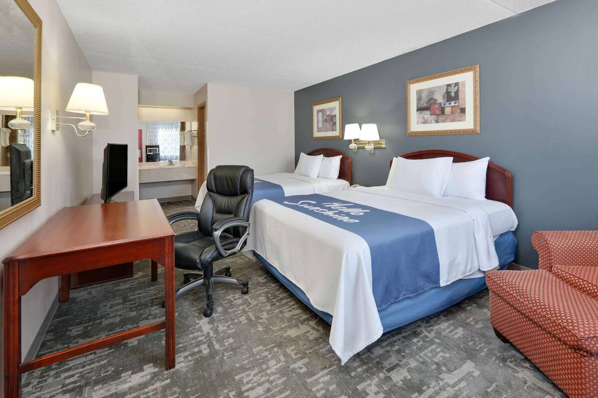 Een hotelkamer met een bed, een bureau, een stoel, een televisie en een spiegel.