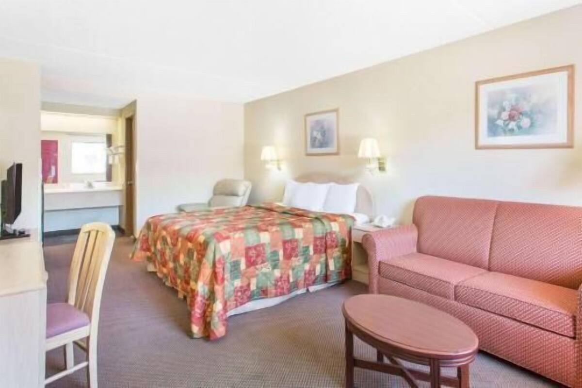 Een hotelkamer met een bed, een bank, een stoel, een tafeltje en een televisie.