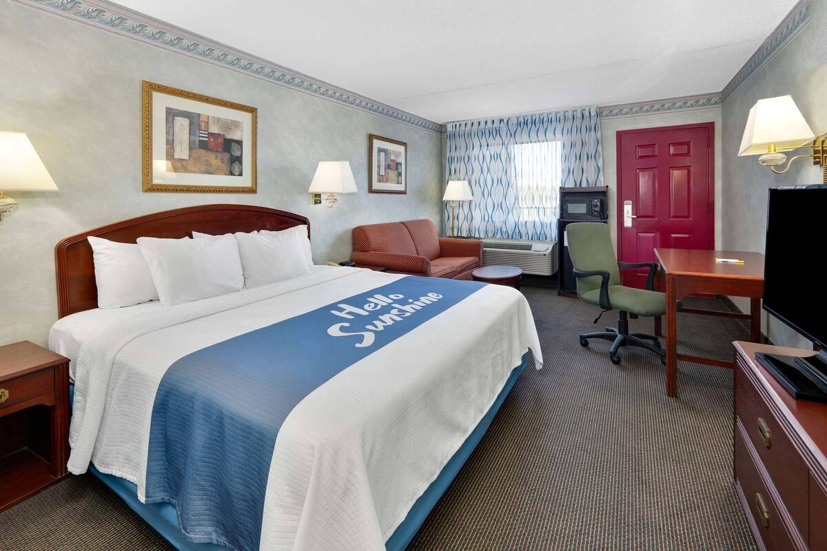 Een hotelkamer met een groot bed, een bureau, een stoel, een televisie en een deur.