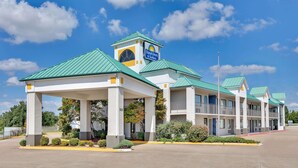 A Days Inn & Suites with a green roof, covered parking, and a clear blue sky.