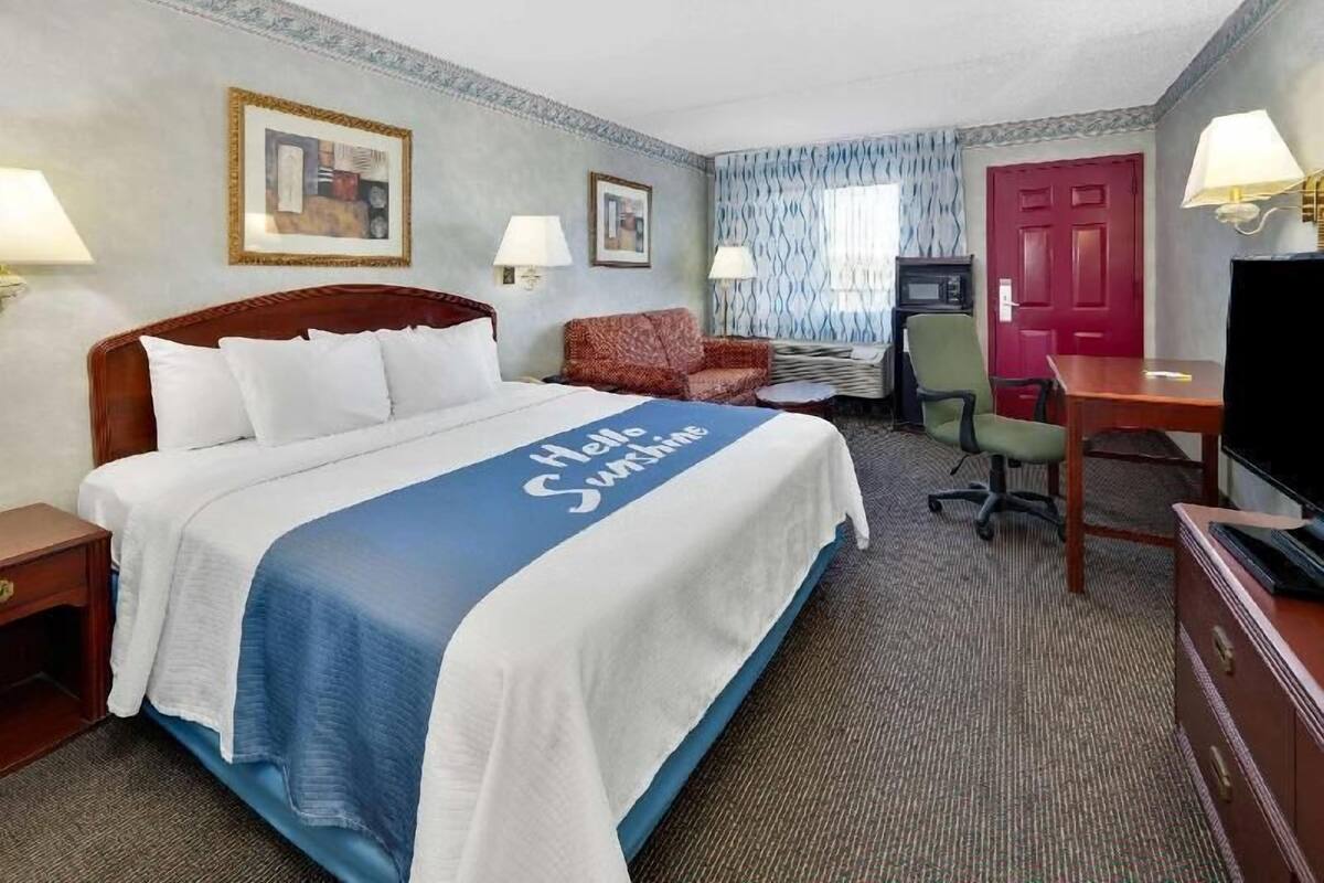 Een hotelkamer met een bed, een bureau, een stoel, een televisie en een deur.