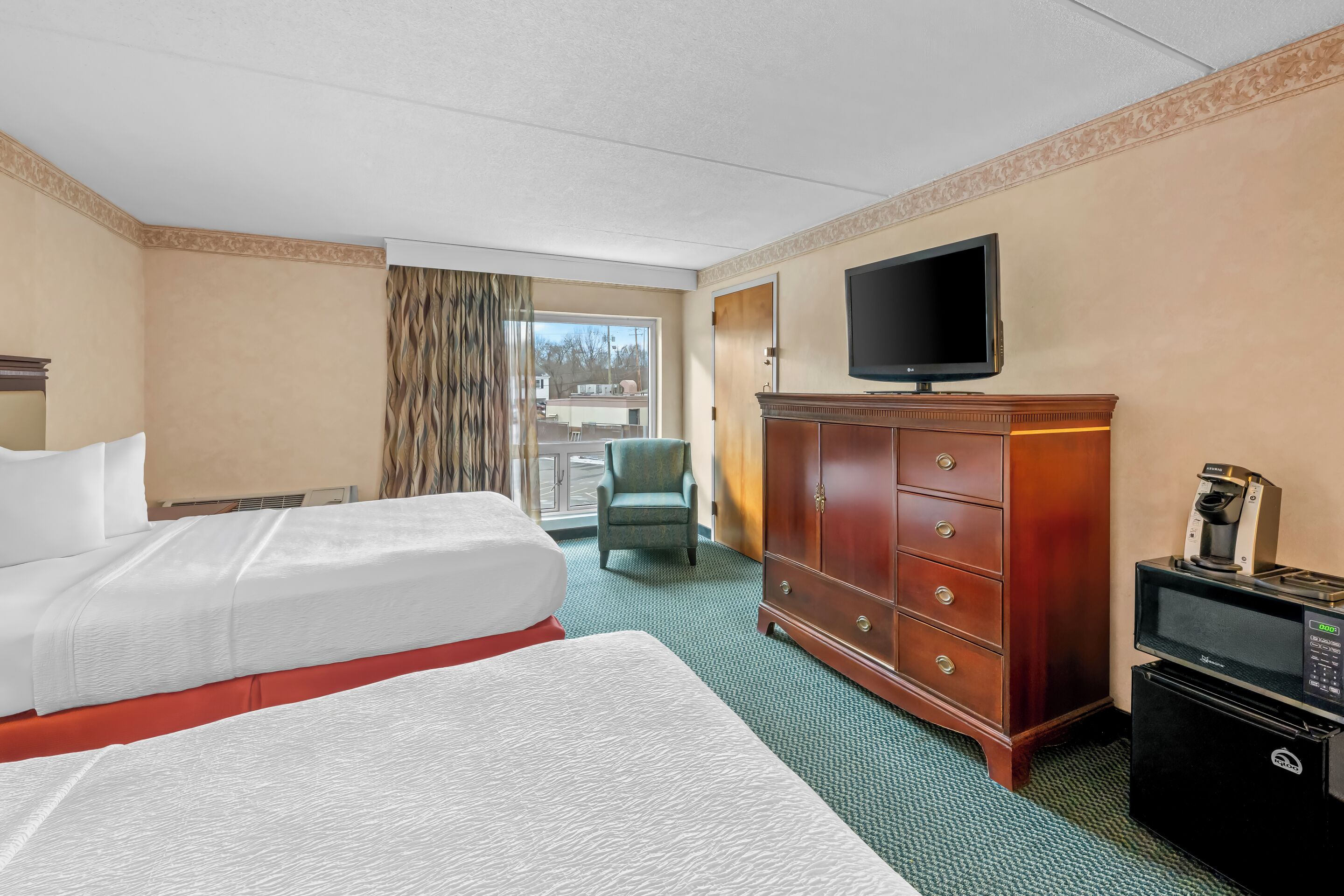 A hotel room with a bed, a television, a cabinet, and a coffee machine.