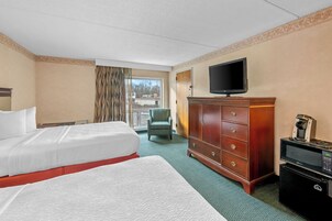 Una habitación de hotel con cama, televisor, armario y cafetera.