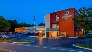 Ein Hotel mit roter Backsteinfassade, Parkplatz und einer amerikanischen Flagge.
