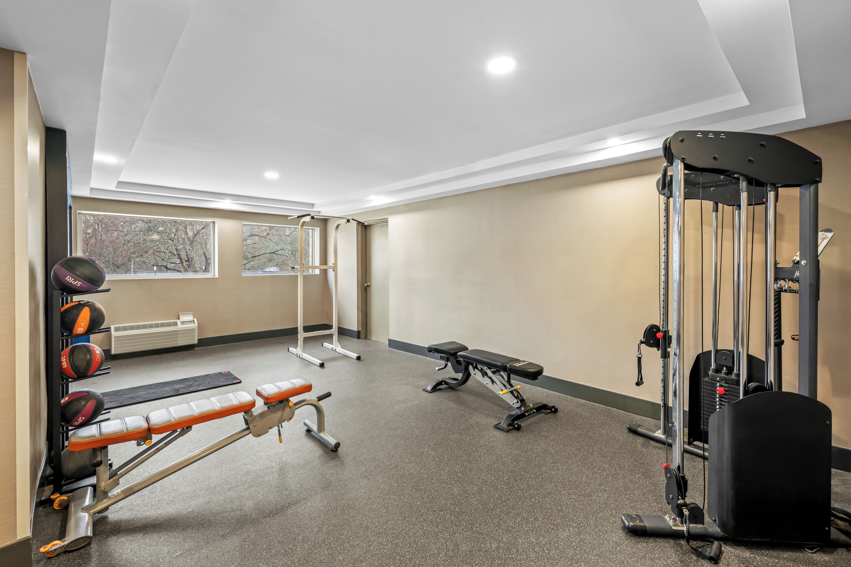 Une salle de sport équipée de matériel d’exercice, d’un banc et d’une fenêtre.