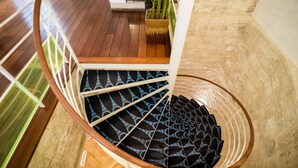A spiral staircase with a patterned carpet, wooden steps, and a white railing. - Hôtel Lorette - Astotel (Paris)