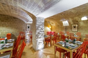 A restaurant with stone walls, wooden tables, and red chairs.