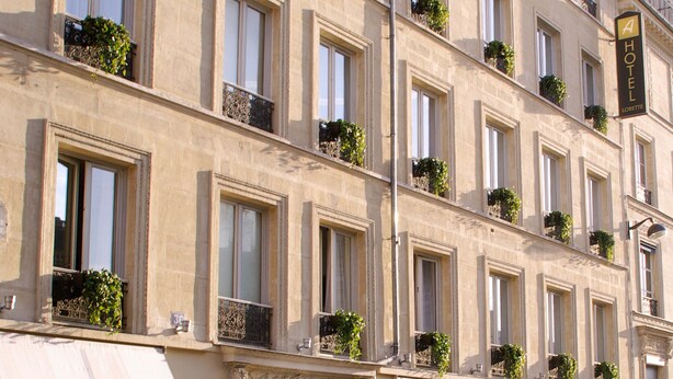 A multi-story hotel with balconies, a wooden door, and a sign indicating a hotel. - Hôtel Lorette - Astotel (Paris)