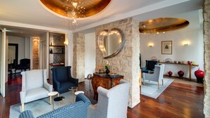 A spacious living room with a stone wall, a heart-shaped mirror, and a wooden ceiling. - Hôtel Lorette - Astotel (Paris)