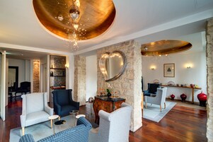A spacious living room with a stone wall, a heart-shaped mirror, and a wooden ceiling.