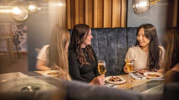 Un grupo de personas cenando en un restaurante con una decoración moderna, que incluye una zona de estar con cojines e iluminación colgante.