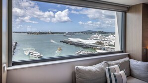 A modern hotel room with a large window offering a view of a harbor with cruise ships and a bridge. - M Social Hotel Auckland (Auckland)